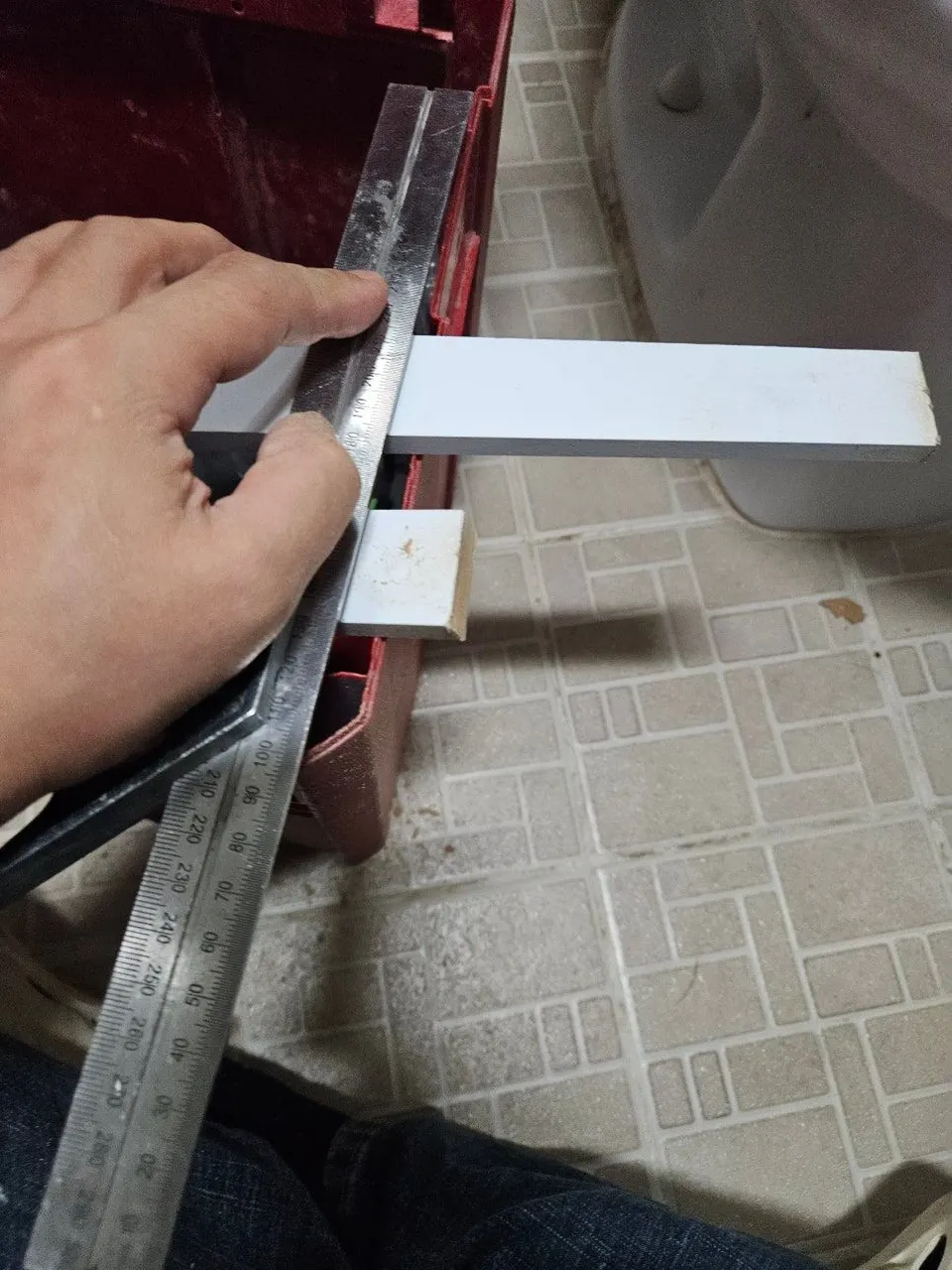 금속 자로 치수를 재어 흰 몰딩 자재를 표시하는 모습