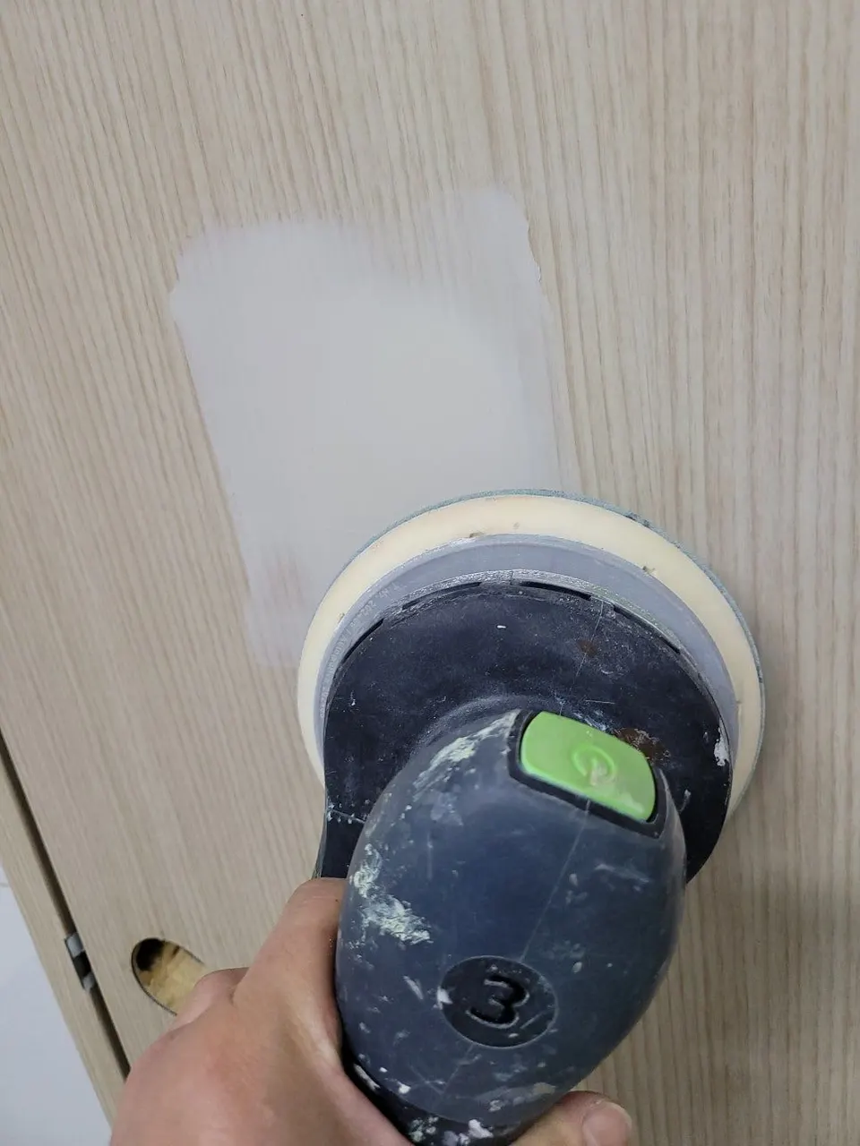샌더로 퍼티를 바른 자리를 갈아 문 면에 맞추는 모습