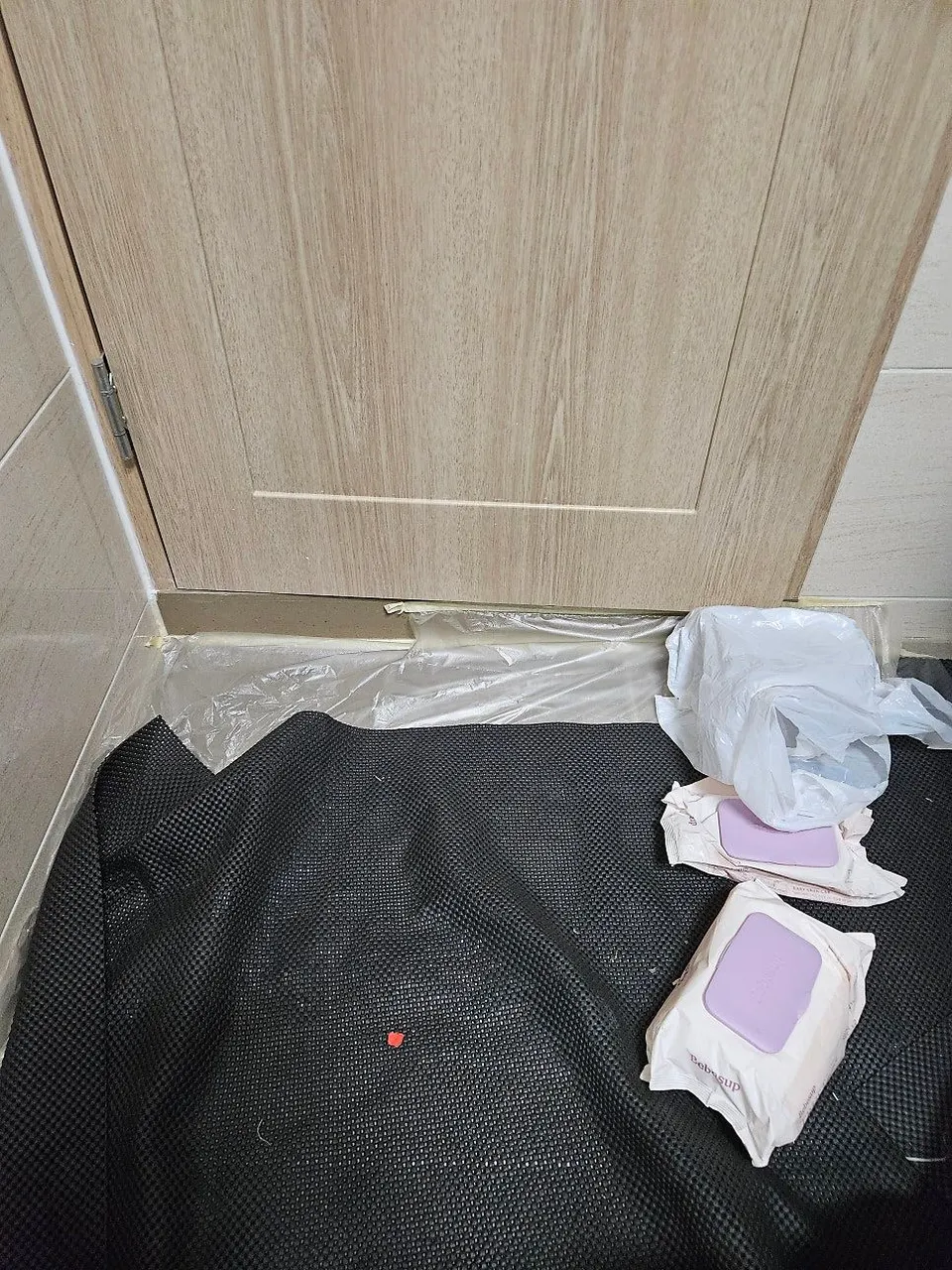 문 아래 바닥에 깔아 둔 보양 매트와 작업 자재